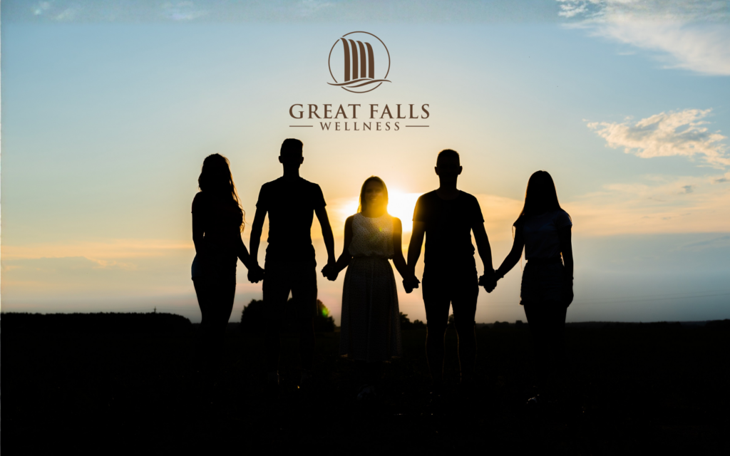 Silhouettes of friends holding hands stands at sunset representing community and solidarity.